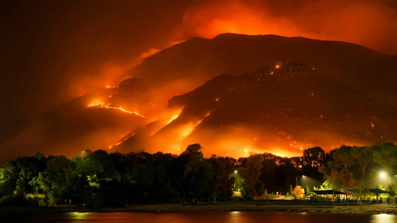 View over water of a wildfire on a mountain. Photo by Mike Newbry on Unsplash