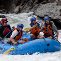 Picture from an Ecogeomorphology Field Trip. Four students and instructors are in a blue whitewater raft on a river