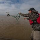 Person throws zooplankton net into floodplain. Net is mid-swing. 