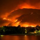 View over water of a wildfire on a mountain. Photo by Mike Newbry on Unsplash